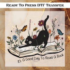 May include: A black cat sits on an open book with the text "It's a good day to read a book". The cat is surrounded by flowers and butterflies.