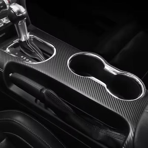 Può includere: Console interna dell'auto con motivo in fibra di carbonio. Include cambio, portabicchieri e freno a mano. Il design è elegante e moderno, con un focus sulla funzionalità e l'estetica.