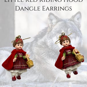 May include: Dangle earrings featuring a miniature Little Red Riding Hood figure. The figure wears a red cape, a plaid dress, and carries a basket. The earrings are from Madame Alexander.