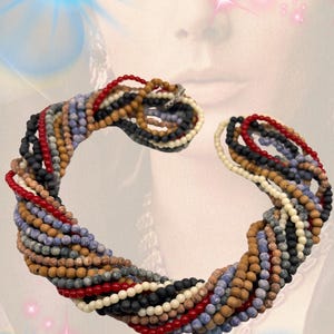May include: A multi-strand twist-a-bead necklace set with a metal clip. The necklace features numerous strands of small, round beads in various colors including red, black, tan, blue, and cream. Text reads: ORIGINAL TWIST-A-BEAD NECKLACE SET WITH CLIP.