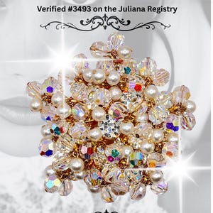 May include: A sparkling brooch featuring a floral design with clear AB crystals and faux pearls. The brooch is accented with gold-tone metal and has the text "Juliana Verified AB Crystal and Pearl Cha-Cha Brooch". Verified #3493 on the Juliana Registry.