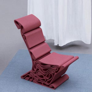 Puede incluir: Una silla única de forma abstracta hecha de una sola pieza de plástico moldeado. La silla es de color rojo burdeos oscuro y tiene una textura acanalada.