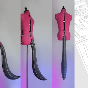 May include: A black fabric tail with a curved tip, attached to a pink dress form. The tail is made of two pieces, with a seam down the centre. The dress form is standing on a white surface.