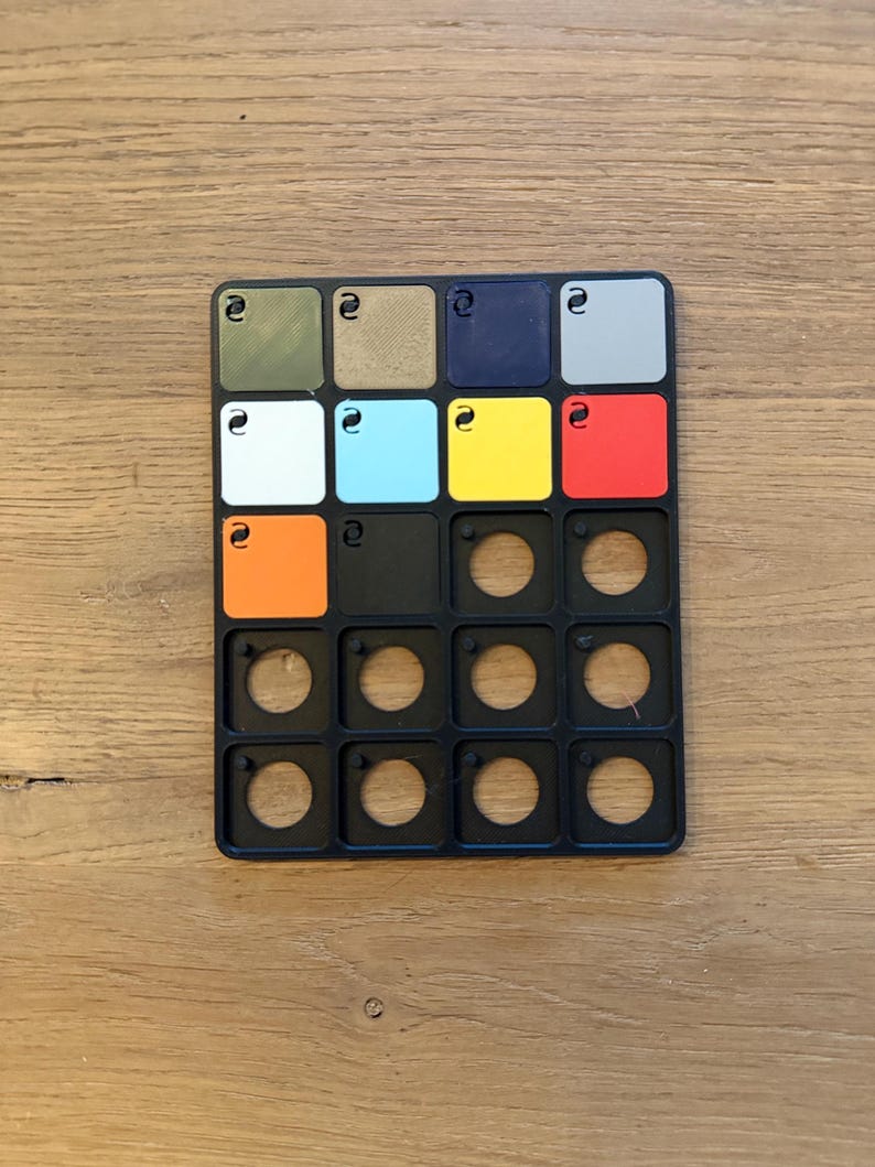 May include: A black colour chart with 18 colour swatches, including green, brown, blue, grey, white, light blue, yellow, red, orange, and black. The chart also has 9 empty circles.