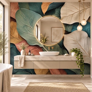 Pode incluir: Um móvel de casa de banho com um lavatório oval branco, um espelho redondo retroiluminado e um mural de parede com grandes folhas sobrepostas em tons de azul-petróleo, dourado e creme. Inclui um armário suspenso bege, dois candeeiros e plantas.