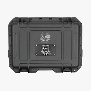 May include: A rectangular black hard-shell protective case with rounded corners and dual latches. The lid features a circular 250 Years logo and a central black rectangular plaque with a white shield emblem and the text Carolina Cases.