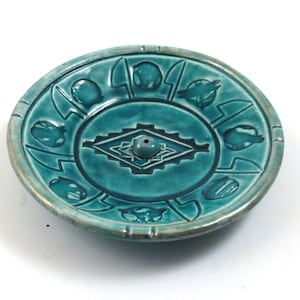 May include: Teal ceramic incense burner with a geometric design and a hole in the center for incense cones.