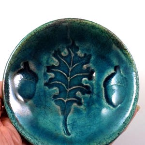 May include: Teal ceramic dish with an oak leaf and two acorns embossed in the center.