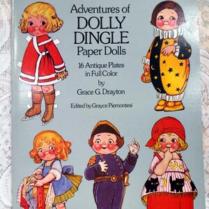 May include: A vintage book cover featuring paper dolls of children in various costumes. The title is "Adventures of Dolly Dingle Paper Dolls" with 16 antique plates in full color by Grace G. Drayton. Edited by Grayce Piemontesi.