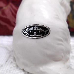 May include: White ceramic figurine with a black and silver label that reads "Jaap Originals".