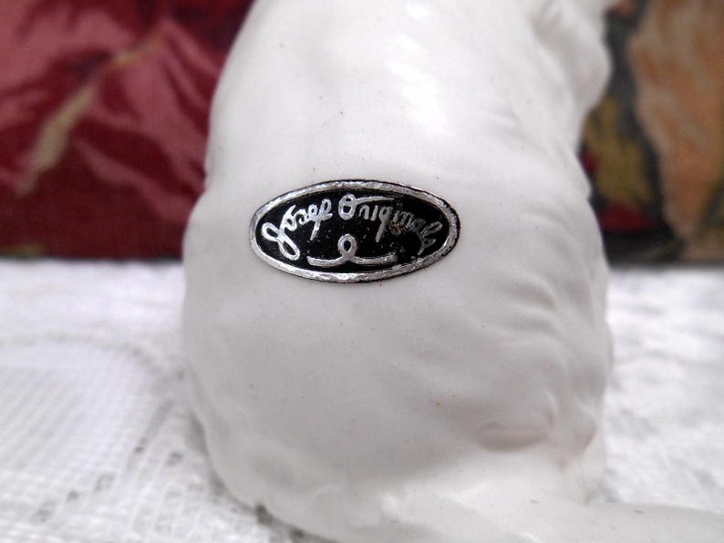 May include: White ceramic figurine with a black and silver label that reads "Jaap Originals".