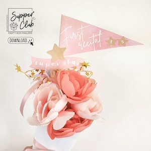 May include: A pink and white flower arrangement with a gold star and a banner that says "super star". A pink pennant with the text "first recital" and gold stars with the numbers 1, 2, and 5 is in the background.