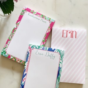 May include: Three personalized notepad sets with floral and striped designs. The notepads feature the names "Katherine Platt", "Erin Duffy", and "Erin".