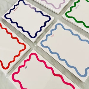 May include: Set of six personalized stationery note cards with wavy borders in various colors, including blue, green, red, pink, and purple. Each card features a different name, including Campbell, Eloise, Mia, Jen, Caitlyn, and another name that is unclear.