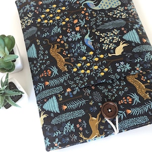 Könnte beinhalten: Eine schwarze Laptoptasche mit einem bunten Blumenmuster mit Pfauen, Hirschen und anderen Tieren. Die Tasche hat einen Klappverschluss und einen braunen Knopf.