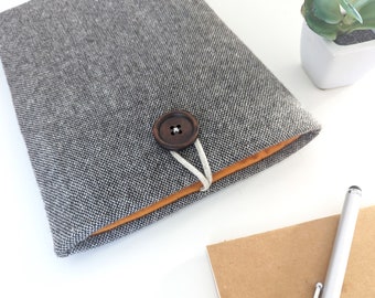 May include: A gray fabric notebook cover with a brown button closure and a light orange lining. The cover has a textured pattern.