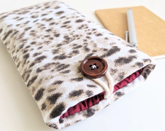 May include: A white and brown leopard print fabric phone case with a brown button closure and a maroon lining.