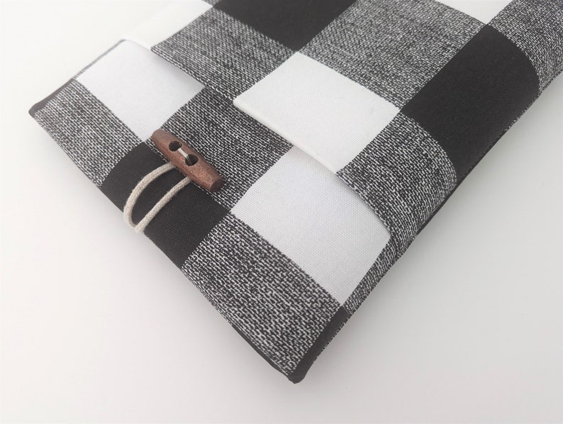 K&ouml;nnte beinhalten: Schwarze und wei&szlig;e karierte Stofftasche mit einem Verschluss aus Holz.
