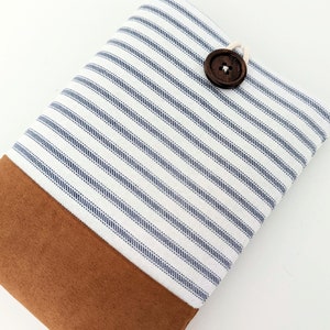 May include: A white and blue striped fabric pouch with a brown suede bottom and a wooden button closure.
