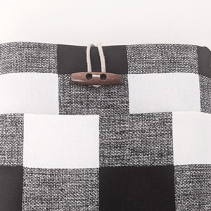 K&ouml;nnte beinhalten: Schwarze und wei&szlig;e karierte Stofftasche mit einem Holz-Knopfverschluss.