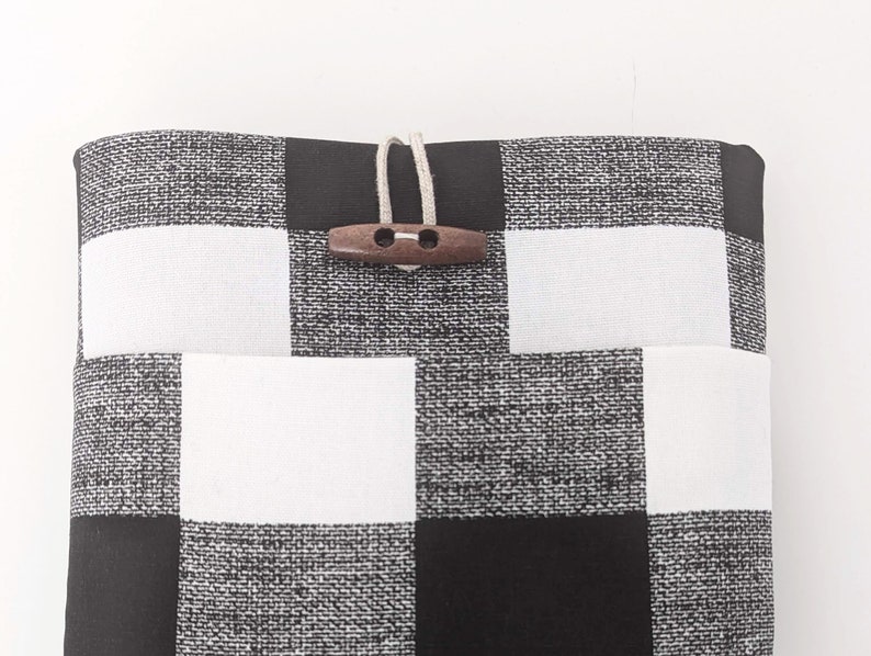 K&ouml;nnte beinhalten: Schwarze und wei&szlig;e karierte Stofftasche mit einem Holz-Knopfverschluss.
