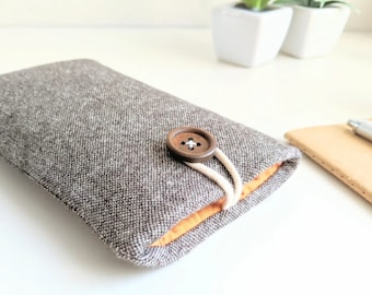 Puede incluir: Una funda para teléfono de tela gris y naranja con cierre de botón marrón.