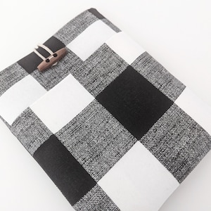 K&ouml;nnte beinhalten: Schwarze und wei&szlig;e karierte Stofftasche mit einem Verschluss aus Holz.