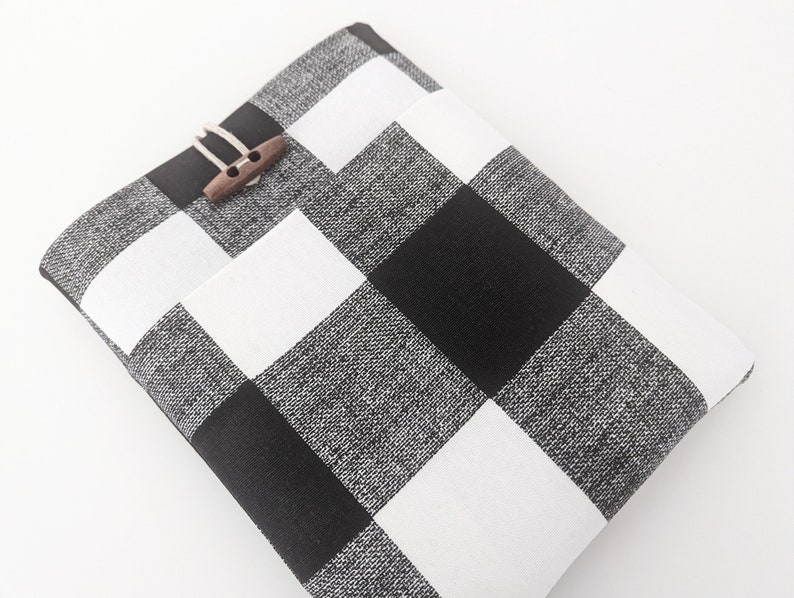 K&ouml;nnte beinhalten: Schwarze und wei&szlig;e karierte Stofftasche mit einem Verschluss aus Holz.