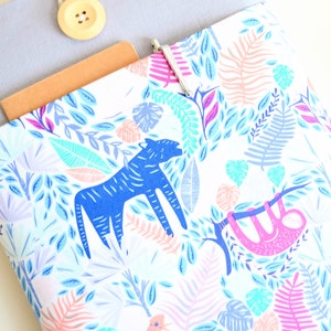 K&ouml;nnte beinhalten: Eine wei&szlig;e Laptoptasche mit einem bunten Dschungel-Druck mit blau-wei&szlig; gestreiften Tieren, rosa und violetten Blumen und gr&uuml;nen Bl&auml;ttern.