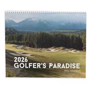 Puede incluir: Un calendario de pared de 2026 con un campo de golf escénico con calles verdes, trampas de arena y un telón de fondo de montañas y árboles de hoja perenne. El calendario se titula "GOLFER'S PARADISE" en letras blancas grandes.