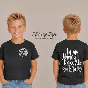 K&ouml;nnte beinhalten: Zwei schwarze T-Shirts mit wei&szlig;em Text und Grafiken. Auf einem Shirt steht "DON'T DO THIS AT HOME FOLKS" mit einer Handgeste. Auf dem anderen steht "In my Johnny Knoxville Era" mit einer Handgeste. Die Shirts werden von einem jungen Mann getragen.