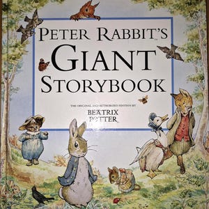 Peut inclure: Un livre de contes intitulé "Peter Rabbit's Giant Storybook" de Beatrix Potter. La couverture présente des illustrations de Pierre Lapin et d'autres personnages dans un champ herbeux. Le titre est en grandes lettres.