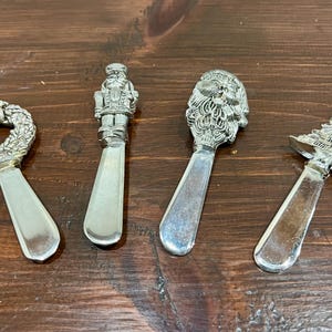 Può includere: Set di quattro coltelli da burro in argento a tema natalizio. I coltelli raffigurano una ghirlanda, uno schiaccianoci, Babbo Natale e un albero di Natale.