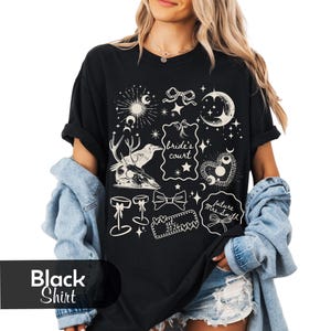 Pu&ograve; includere: Maglietta nera con grafica color crema con elementi celesti e botanici. Il design include lune, stelle, fiocchi e il testo "Bride's Court" e "future Mrs. Smith". La maglietta presenta anche un teschio di cervo e altri elementi decorativi.