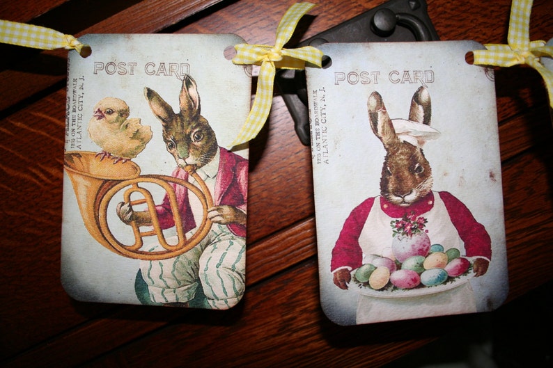 May include: Two vintage postcard style images with a bunny rabbit theme. The first image features a brown bunny rabbit holding a french horn with a yellow chick beside it. The second image features a brown bunny rabbit wearing a chef's hat and apron holding a plate of colorful Easter eggs. Both images have the text "POST CARD" printed on them.