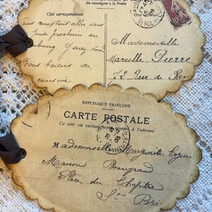 Puede incluir: Dos postales francesas vintage con bordes festoneados y escritura manuscrita. Una tiene un sello y dice "CARTE POSTALE". La otra tiene una cinta adjunta. Las postales est&aacute;n envejecidas con un tono sepia.