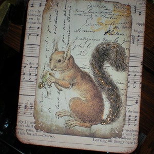 Pode incluir: Uma etiqueta retangular com um design vintage com um esquilo marrom segurando uma noz. A etiqueta tem um aspecto envelhecido com escrita e notas musicais no fundo. O texto "HAPPY PILGRIMS" est&aacute; no topo, com uma fita marrom e verde.