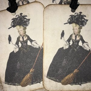 May include: Vintage-style gift tags featuring a woman in a black gown, holding a crow and a broom. The woman has blonde hair and wears a large black hat. The tags have a distressed, aged appearance with a black ribbon.