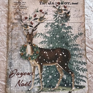 May include: A vintage Christmas card featuring a brown deer with a green wreath around its neck standing in a snowy forest. The card has a white background with a grid pattern and the text "Joyeux Noël" in brown lettering.
