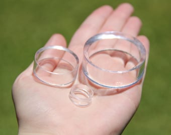 May include: Three clear plastic rings of different sizes. The rings are stacked on top of each other.