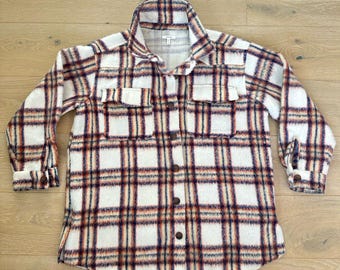 May include: A white, long-sleeved flannel shirt with a plaid pattern in shades of brown, red, and blue. The shirt has a button-up front and two chest pockets.