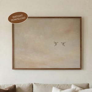 May include: A framed print featuring two hummingbirds in flight, set against a soft, neutral-toned background. The artwork is enclosed in a dark brown wooden frame. The text "INSTANT DOWNLOAD" is displayed on a brown oval in the upper left corner.
