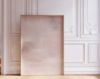 May include: A large, rectangular framed artwork with a soft, abstract design in shades of pink and beige. The artwork leans against a white wall with ornate molding, set on a herringbone wood floor.