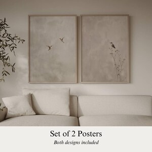Op de afbeelding: Set van twee ingelijste posters. E&eacute;n poster toont vogels in vlucht, de andere een vogel op een plant. Beide posters hebben een neutraal kleurenpalet en worden boven een cr&egrave;mekleurige bank getoond. De tekst luidt: 'Set of 2 Posters'.