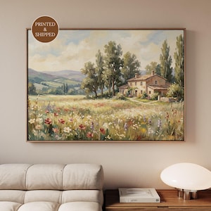 Könnte beinhalten: Gerahmtes Landschaftsgemälde, das ein Feld mit Wildblumen vor einem Steinhaus und Bäumen zeigt. Das Kunstwerk hat eine warme Farbpalette mit Grüntönen, Gelb und Rot. Das Gemälde befindet sich in einem goldenen Rahmen.