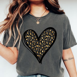 May include: A gray t-shirt with a black outlined heart design filled with a gold and black leopard print pattern.