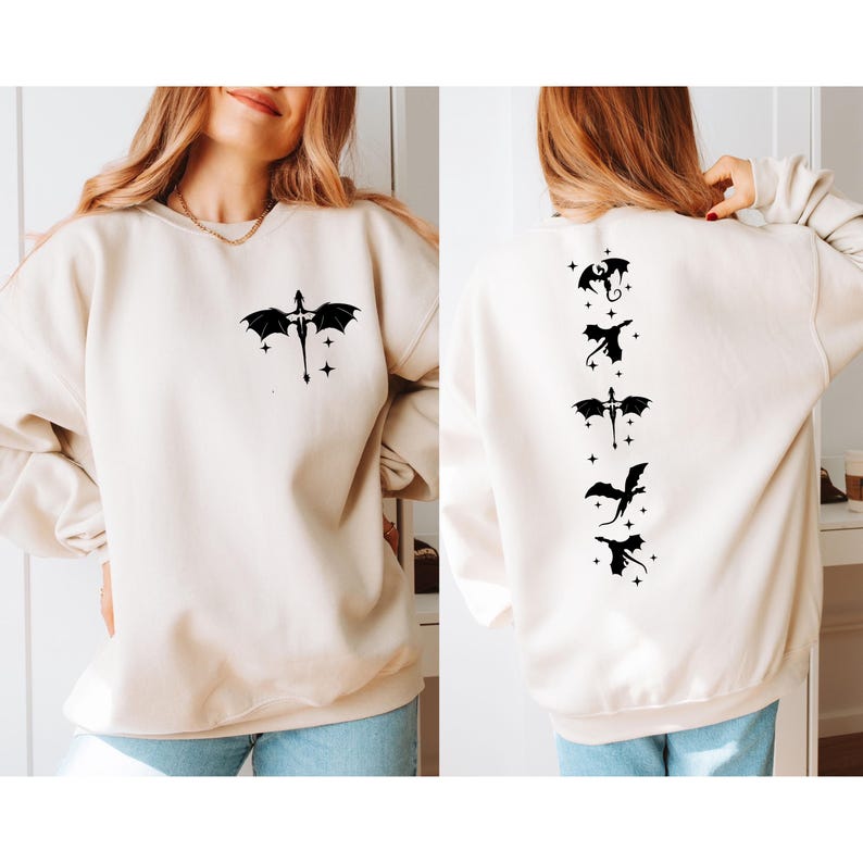 May include: A cream colored sweatshirt with a black dragon design on the front and five black dragons on the back. The dragons are flying with stars around them.