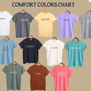 May include: A color chart of t-shirts in various colors, including white, pepper, butter, violet, grey, ice blue, black, ivory, seafoam, moss, yam, and watermelon. The chart is labeled "COMFORT COLORS CHART".