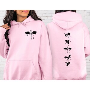 May include: Pink hoodie with a black dragon design on the front and a series of black dragon designs on the back.