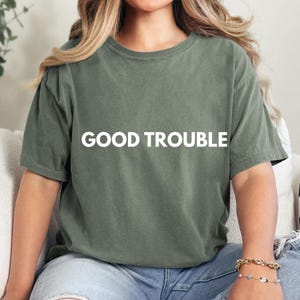 May include: A green t-shirt with the text "GOOD TROUBLE" printed in white on the front.